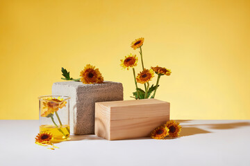 A block of stone and a rectangle wooden podium are arranged with a beaker of liquid and Calendula...