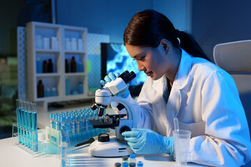 Asian scientist looking at a microscopic sample of experimental cyan is doing an in vitro vaccine...