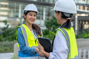 Asian Technician, Engineer doing handshake together with a cityscape in the background