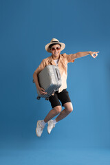 Portrait of Asian man posing on blue background, traveling in summer