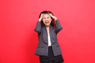 indonesia office woman's expression, severe pain, headache, both hands holding the camera, wearing a gray jacket and red skirt. for health, business and advertising concepts