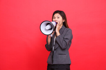 Asian office woman's expression tilted to the right, shouting angrily using a megaphone, hand...
