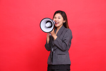 the expression of a cheerful Asian office woman shouting using a megaphone in front of her wearing...