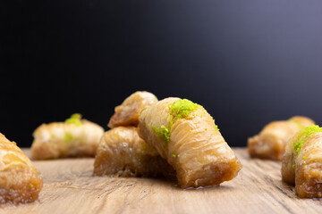 Turkish Baklava on plate with pistachio on top. Dessert on desk with dark color background.
