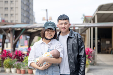 A mother and father in their 20s living in Yilan, Taiwan, are in a car holding a one-month-old...