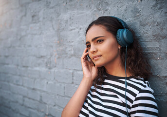 City, thinking and girl with headphones, streaming music and smile on grey wall with mindset and calm thought. Gen z, outdoor and headset for radio, listening to audio and sound with peace and relax