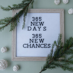 365 NEW DAYS 365 NEW CHANCES text on white letter board on green background with Christmas decor....