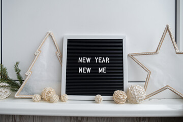 NEW YEAR NEW ME text on black letter board with cozy minimalistic handmade Christmas decor. New year aims resolutions. Low key festive Planning and setting goals concept