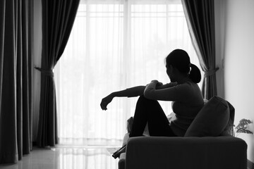 Depressed woman, Silhouette of teenager girl with depression sitting alone  in the dark room. Black...
