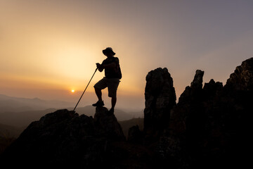 Silhouette of hiker standing on top mountain sunset background. Hiker men's hiking living healthy active lifestyle.
