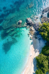 Fototapeta premium An aerial perspective of a hidden beach with turquoise water surrounded by rocky outcrops and lush trees.