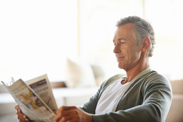 Mature, man and newspaper for reading in home, relax and information or articles in morning with coffee. News, breakfast table and rest and calm for entertainment pages, current events in apartment