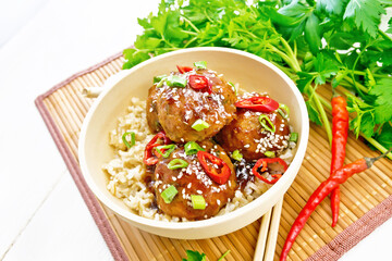 Meatballs in sweet and sour sauce with rice on light board