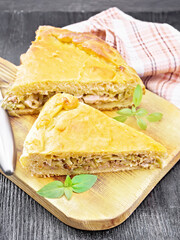Pie with meat and cabbage on dark wooden board