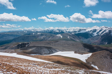 Snowy stony pass, large colorful mountain range and valley in far away. Snow-white glacier in...