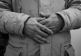 Close up of old man's crossed hands resting on stomach. black and white photo