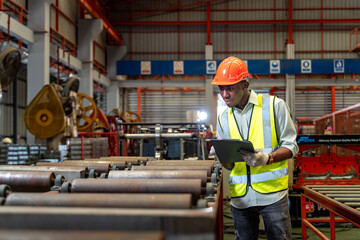 African American industrial worker is checking setup value of metal sheet roll forming machine...