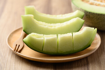 Green melon fruit on wooden plate ready to eating