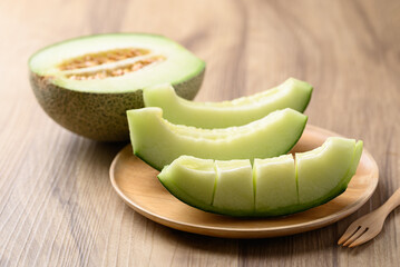 Green melon fruit on wooden plate ready to eating