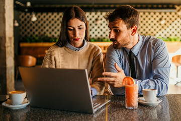 Shot of two people having a coffee at a coffee shop with a laptop in front of them