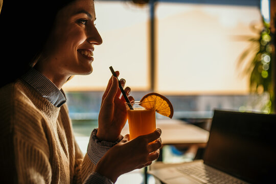 Beautiful smiling young woman drinking fresh orange juice at the bar. copy space