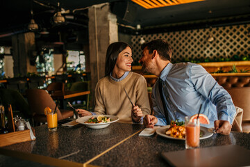 Cheerful couple sitting in a restaurant, having lunch and chatting