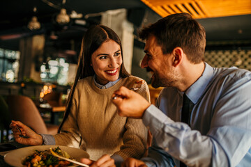 A loving couple laughing while eating in the restaurant afterwork