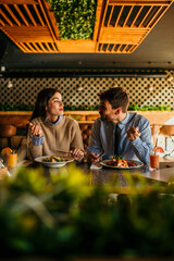 Happy young woman eating lunch with her boyfriend in a restaurant