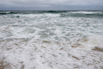 View of the surf on the snowing sand beach