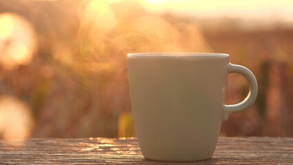 Coffee cup nature outdoor background. Steaming hot coffee, tea cup on old wooden table against...