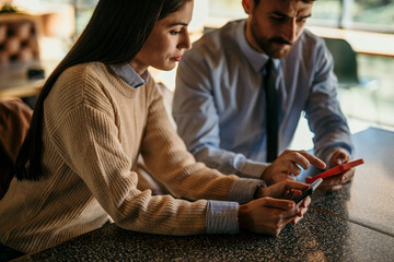 Shot of a young man and woman having a meeting in a cafe and using a phones