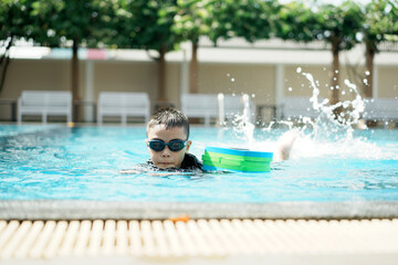 	
A little asian boy in swimming in the pool. Cute girl playing in outdoor swimming pool on a hot...