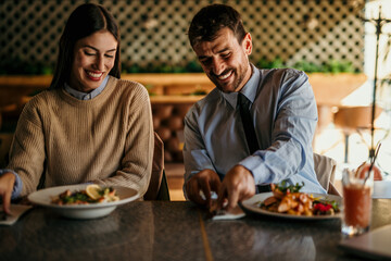 Cheerful elegant couple eating together and having fun in a restaurant