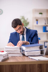 Young male employee and too much work in the office