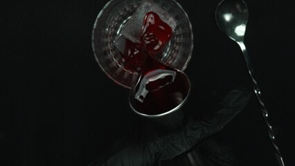 Top down view of bartender hand making and prepare Scarlet spritzer with black background. Close up...
