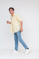 Full body photo of a handsome young asian man in an unbuttoned yellow polo and white shirt and blue...