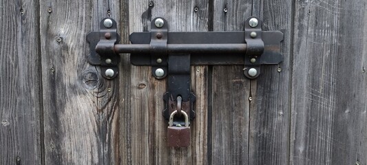Metal lock on a wooden door, gate, old locking system
