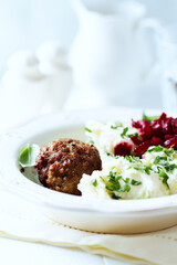 Hamburger steak with potatoes and fresh herbs on bright background. Close up.	