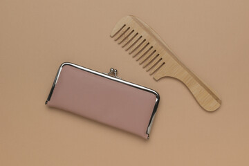Beige purse and wooden comb on beige background.