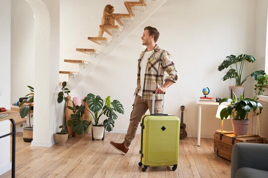 Portrait handsome young man walking with suitcase house renting room vacation smiling