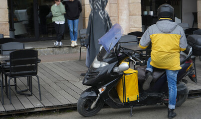 food delivery courier delivers food in city, town. Delivery courier motor scooter with yellow...