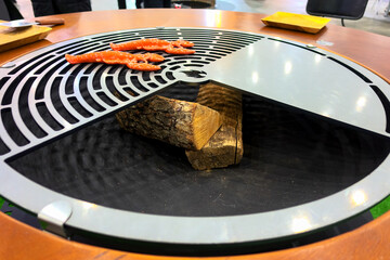 Round grill surrounded by a wooden dining table.