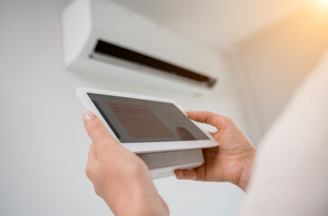 Young woman operates wireless aircon system in a modern apartment.