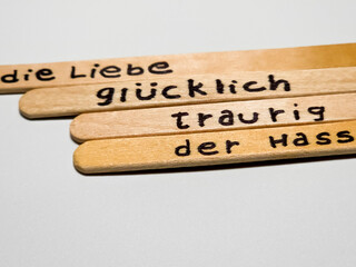 close up of a hand written german words on  popsicle sticks as a self esteem building concept, emotion, love, happy, sad, exited, hate, mood, activities.