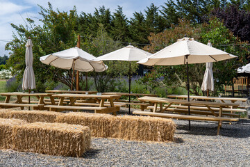 Empty countryside outdoor cafe with wooden tables, umbrellas and hay briquettes