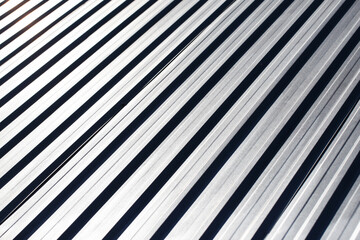 Corrugated aluminum roofing. Sunlight metal stripes. Striped pattern. Home roof. Geometric lines shiny aluminim. Metal industry texture.