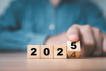 Businessman flipping of 2024 to 2025 on wooden block cube for preparation new year change and start new business target strategy concept.