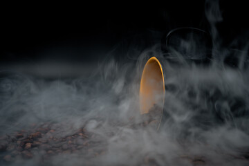 coffee beans and cup on black close up with smoke of brew