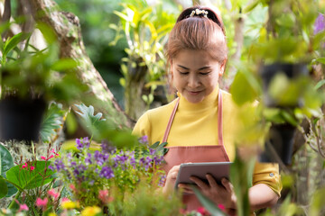 Gardener asia woman receipt order customer and sale plant flower online on laptop in garden. People...
