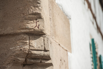 Historisches Gebäude mit Steinmetzzeichen an Eckstein aus Sandstein und verputzter weißer Wand
